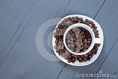 Cup with coffee beans inside on grey wooden background Stock Photo