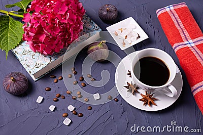 A cup of coffee, coffee beans and sugar cubes, a book and a branch of hydrangea Stock Photo