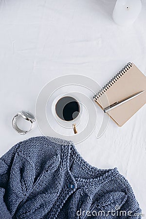 Cup coffee , blue knitted sweater, notebook with pen, clock, candle on bed, top view Stock Photo