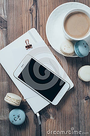 Cup of coffee, blue macaroons and smartphone on wooden table bac Stock Photo