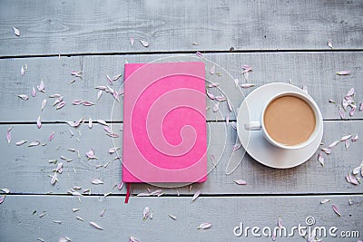 A cup of coffee, a bouquet of flowers, a diary, a notebook, a pink pen and a phone on a gray background, Stock Photo