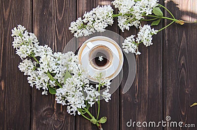 A Cup of coffee and a branch of lilacs on a wooden table Stock Photo