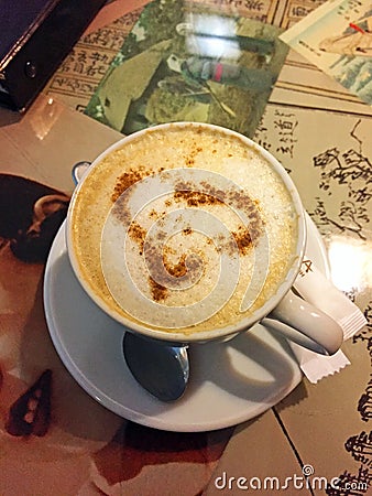 A Cup of coffee cappuccino with a heart of cinnamon on the table in the cafe Stock Photo