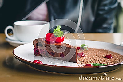 A cup of coffee with a chocolate brownie cake with cherries and mint Stock Photo