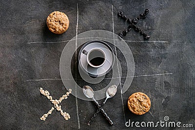 Cup of coffee, cookies, pair of spoons, oatmeal, raisins in the composition and form of tic-tac-toe game on stone Stock Photo