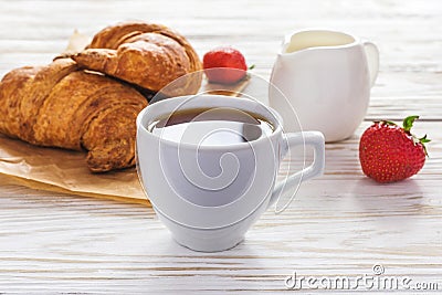 Cup of coffee, croissants, strawberry and milk jar Stock Photo