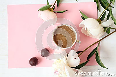 A Cup of coffee with delicate peonies and two chocolates on a rose background, top view-a place for text-the concept of a pleasant Stock Photo