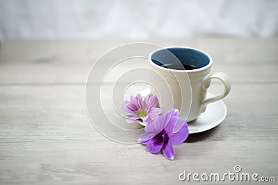 Cup of coffee with flowers. Morning coffee concept with soft purple orchid daisy flower on white table bright background. Stock Photo