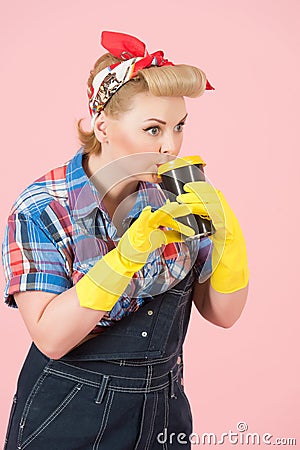 Cup of coffee in hands of girl with blonde curls. Pin-up style and craft cup of coffee. Woman drinks coffee in latex gloves Stock Photo