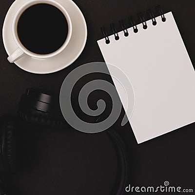 Cup of coffee, headphones, notepad on a black background. Stock Photo