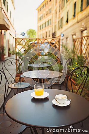 A cup of coffee and juice on table, in italian street, mediterranean style. Street view of a summer terrace Stock Photo