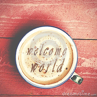 Cup of coffee latte, cappuccino on a pink wood table. Words welcome world written on a coffee top. Stock Photo