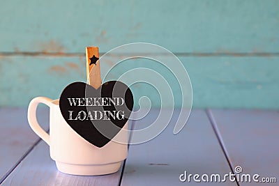 Cup of coffee and little heart shape chalkboard with the phrase: WEEKEND LOADING. Stock Photo