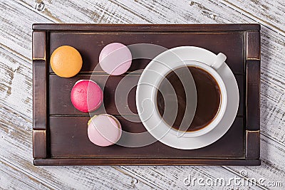 Cup of coffee and macaron cakes on tray on white wooden table. Lifestyle concept. Stock Photo