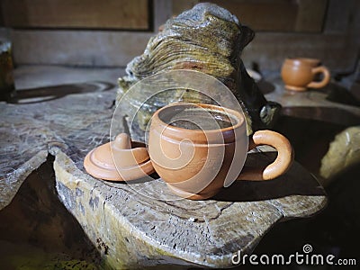 A cup of coffee made from clay on a wooden table made from teak wood roots Stock Photo