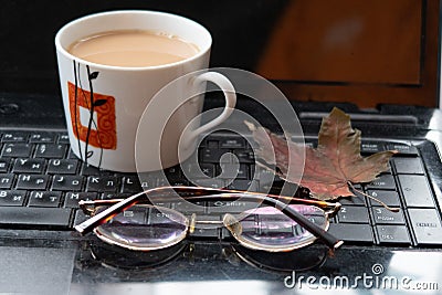 Cup of coffee, maple leaf and glasses on laptop keyboard, earnings on the Internet, freelancer Stock Photo