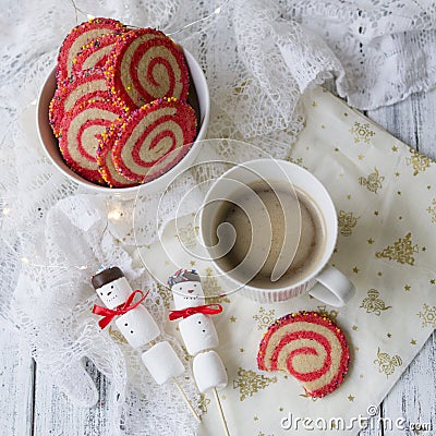 Cup of coffee with a marshmallow snowman and cookies in the form of a spiral in the Christmas table. Cozy winter breakfast. New Ye Stock Photo