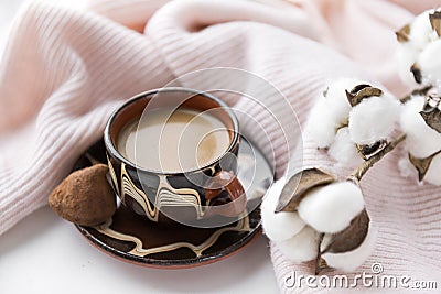 Cup of coffee with milk, candy, cotton twig, pink knitted fabric Stock Photo