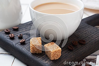A Cup of coffee with milk and cubes of cane sugar on a wooden stand. Background of white rustic boards. Copy space Stock Photo