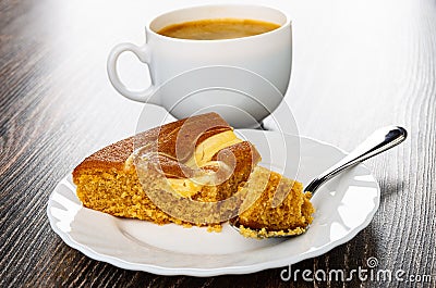 Cup with coffee, slice of Ñake with cream and jam, spoon with piece of cake in plate on wooden table Stock Photo