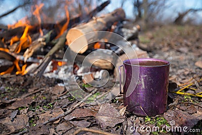 Cup with coffee is standing next to a campfire Stock Photo