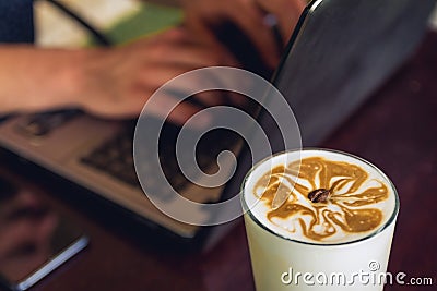 A cup of coffee on the table with laptop and human hands on the keyboard. Stock Photo