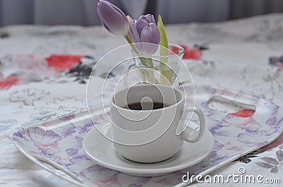 a cup of coffee tray with spring flowers on pink bedding. Relaxing, or working, or writing diary or blog in bed at home Stock Photo