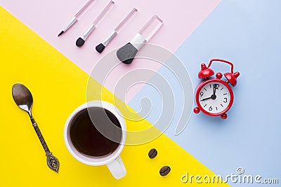 Cup of coffee, Watch the Clock and make-up brushes on colorful backgrounds. Concept business morning. Stock Photo