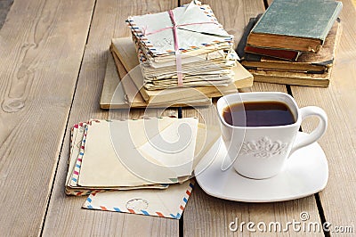 Cup of coffee on wooden table. Vintage books and pile of letters Stock Photo