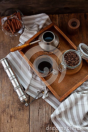 A cup of coffee on a wooden tray. Turk and coffee beans. Cook breakfast at home. Still life with a drink in a glass. Ground coffee Stock Photo