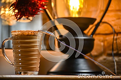 A cup of delicious coffee on the background of a luminous lamp that stands on the windowsill, New Year`s decor room Stock Photo