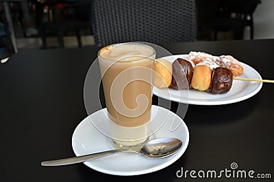 Cup of delicious foamy coffe and dessert on a black table. Stock Photo