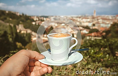 Cup of espresso coffee in hand of tourist and cityscape of Florence in perspective, Italy. Good morning concept Stock Photo