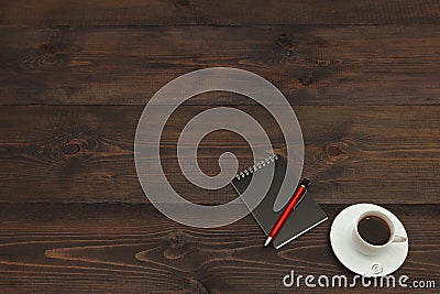 Cup of espresso, pen and black notebook on wooden desktop. View from above Stock Photo