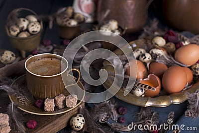 A cup of fragrant coffee and brown sugar. Vintage photo. Eggs chicken and quail and feathers. Easter. Photo in a rustic style. Stock Photo