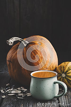 Cup of fresh pumpkin juice, ripe pumpkins and seeds on table Stock Photo