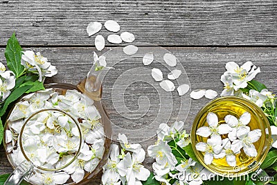 Cup of green herbal tea with jasmine flowers and teapot over rustic wooden background Stock Photo