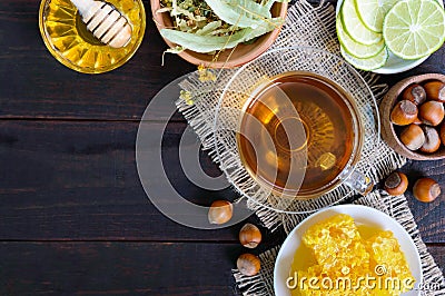 A cup of herbal tea, honey, honeycomb, hazelnuts on a dark wooden background Stock Photo