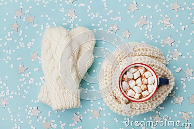 Cup of hot cocoa or chocolate with marshmallow and knitted mittens on blue winter background top view. Flat lay. Stock Photo