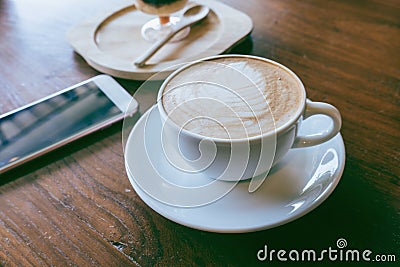 Cup of hot coffee ad smartphone put on old wooden table background Stock Photo