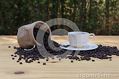 A cup of hot coffee and roasted coffee beans in a bag with bokeh background Stock Photo