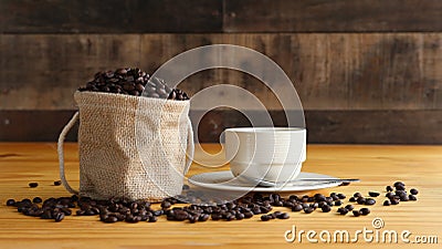 A cup of hot coffee with roasted coffee beans in warm light with wood background Stock Photo