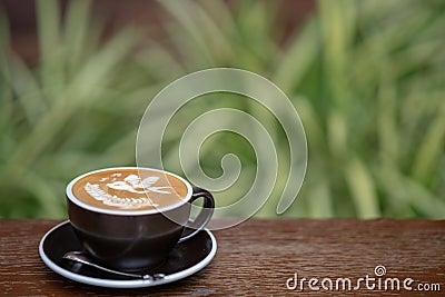 A cup of hot latte art coffee on wood table. Stock Photo