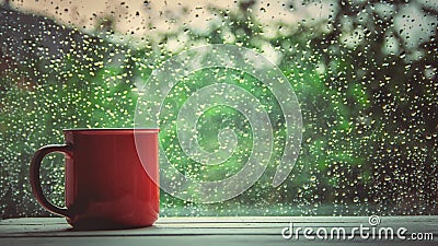 A cup of hot tea in the background rain outside the window. Stock Photo