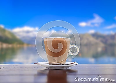 Cup of latte coffee with a blurred view of Kotor Bay or Boka Kotorska in background in Montenegro, on the Adriatic Sea Stock Photo