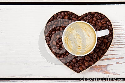 Cup of latte coffee with foam over coffee bean heart. Stock Photo