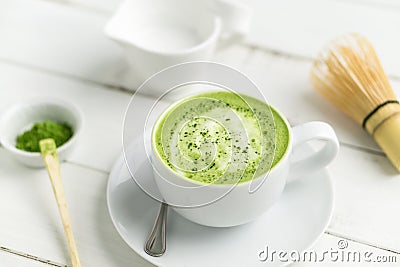 Cup of matcha green tea latte with accessories in background. Stock Photo