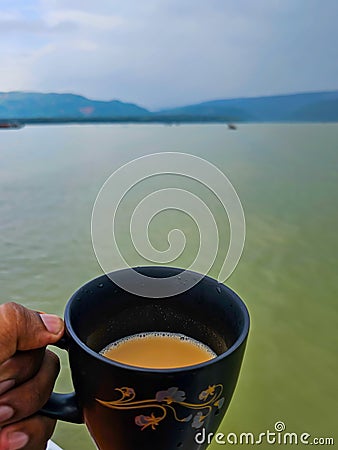 A cup of milk tea with the view of the hills of Meghalaya from the Tanguar Haor in Sylhet, Bangladesh Stock Photo