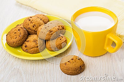 Cup of milk, yellow napkin, cookies on saucer on table Stock Photo