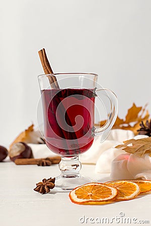 A cup of mulled wine with spices, scarf, spices, dry leaves and oranges on the table. Autumn mood, a method to keep warm in the Stock Photo